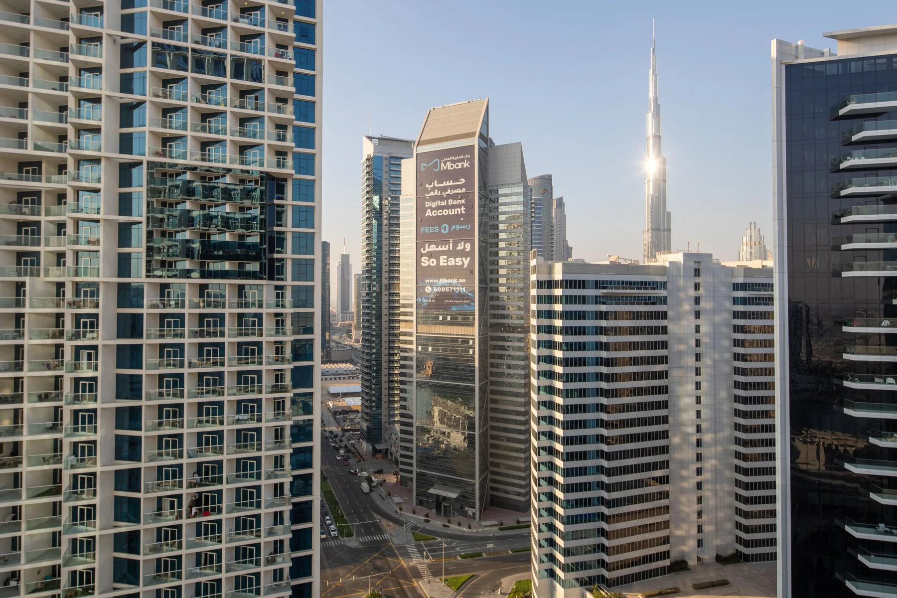 A city skyline with high-rise buildings and a slender tower in the distance.