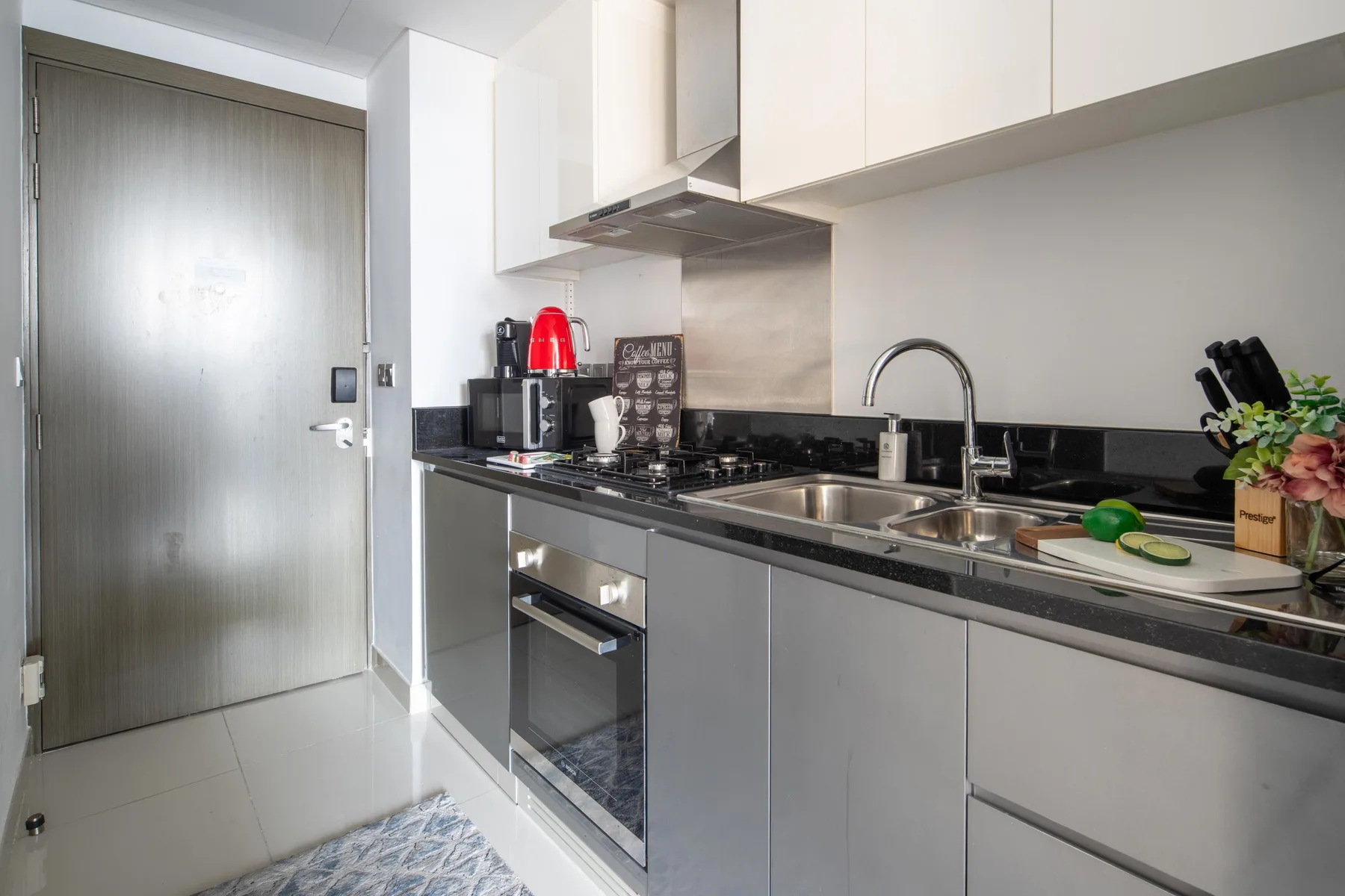 A compact kitchen with gray cabinets, a cooktop, and a sink.