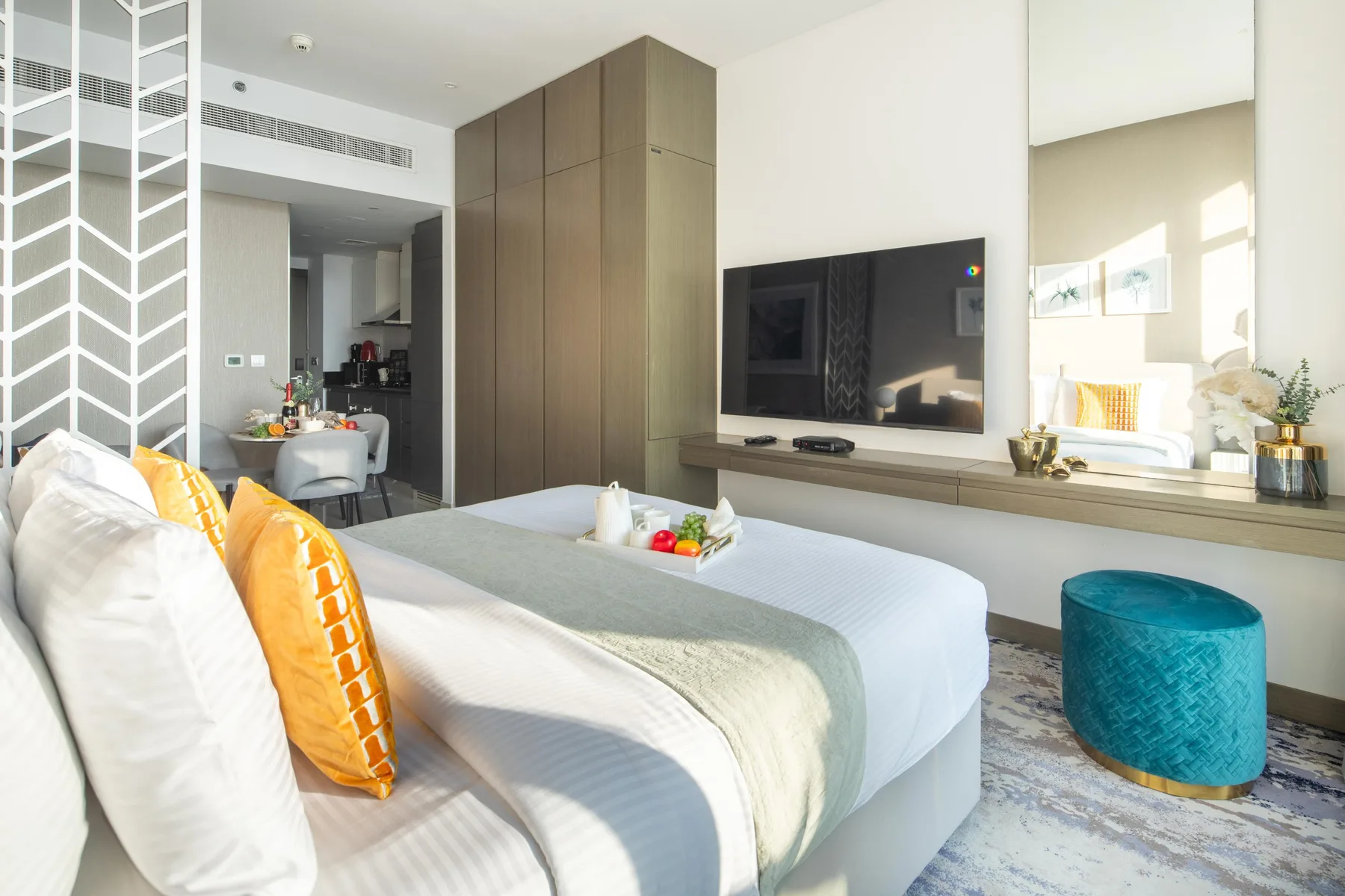 A bedroom with a bed, a wall-mounted television, and a small blue seat.