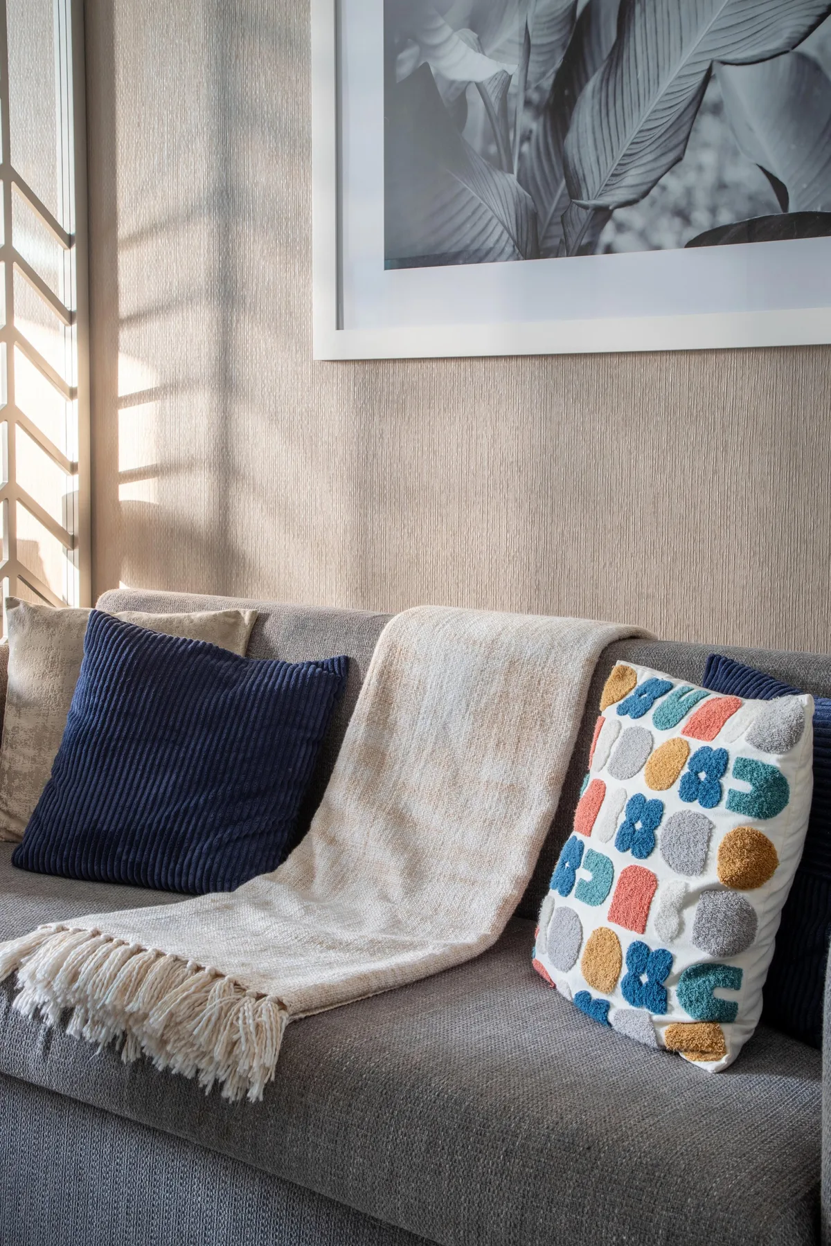 A living room seating area with a sofa, cushions, and framed botanical artwork.