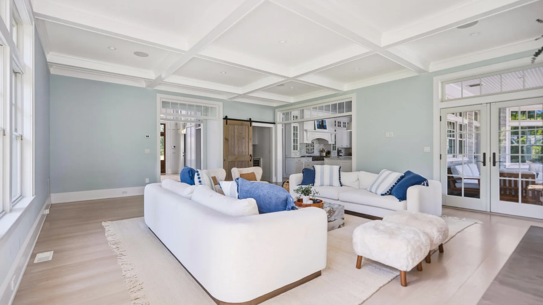 A bright living room with white seating and large windows.