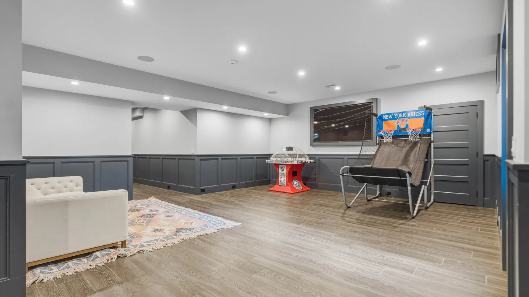 A finished basement recreation room with seating and a small basketball game.