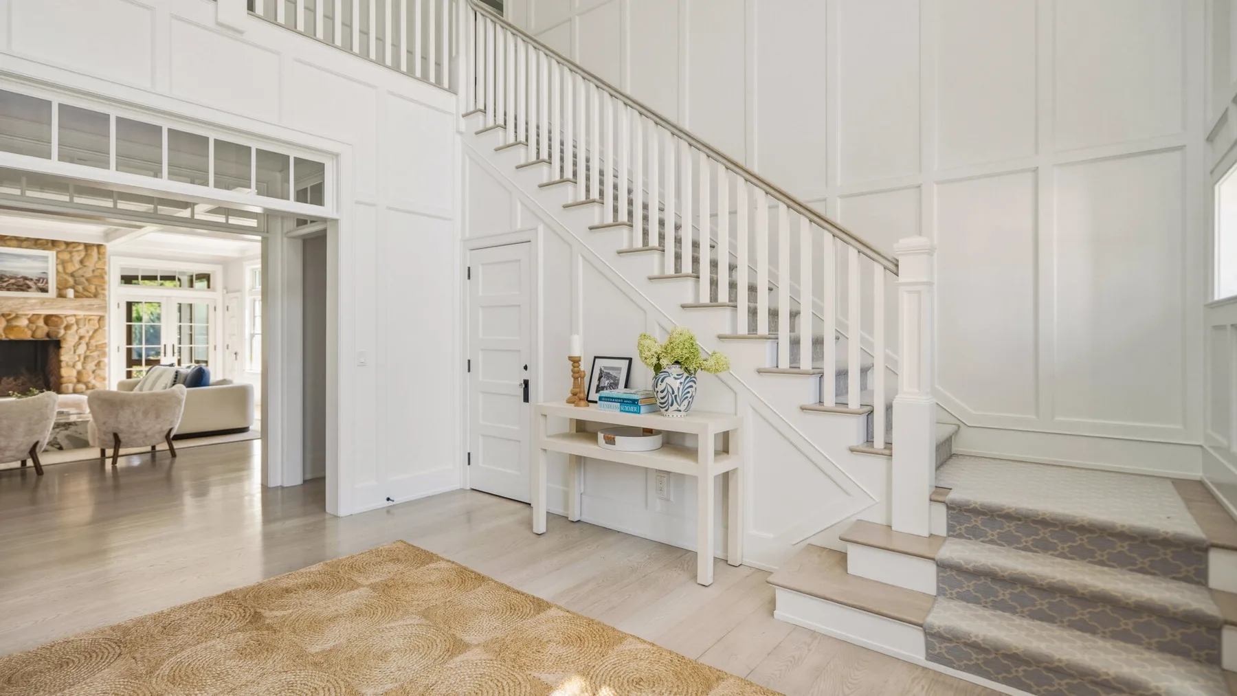 A bright entry hall features a staircase and a small table beneath it.