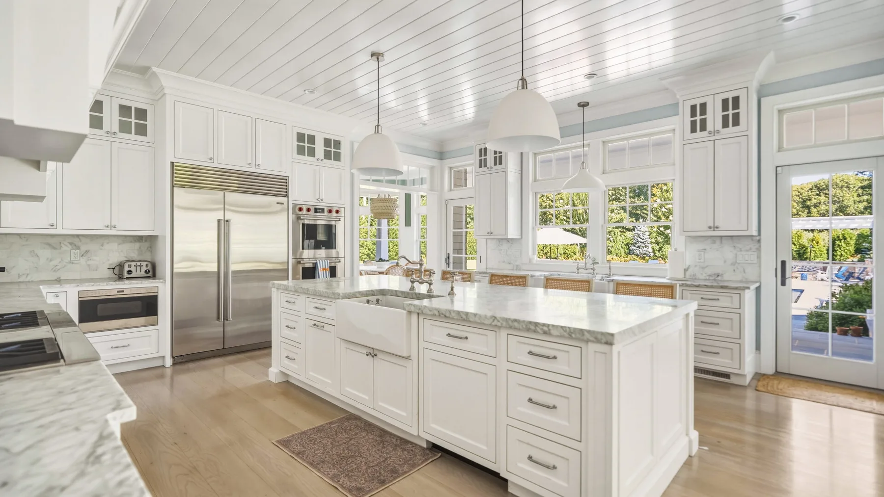 A bright white kitchen with a central island and stainless steel appliances.