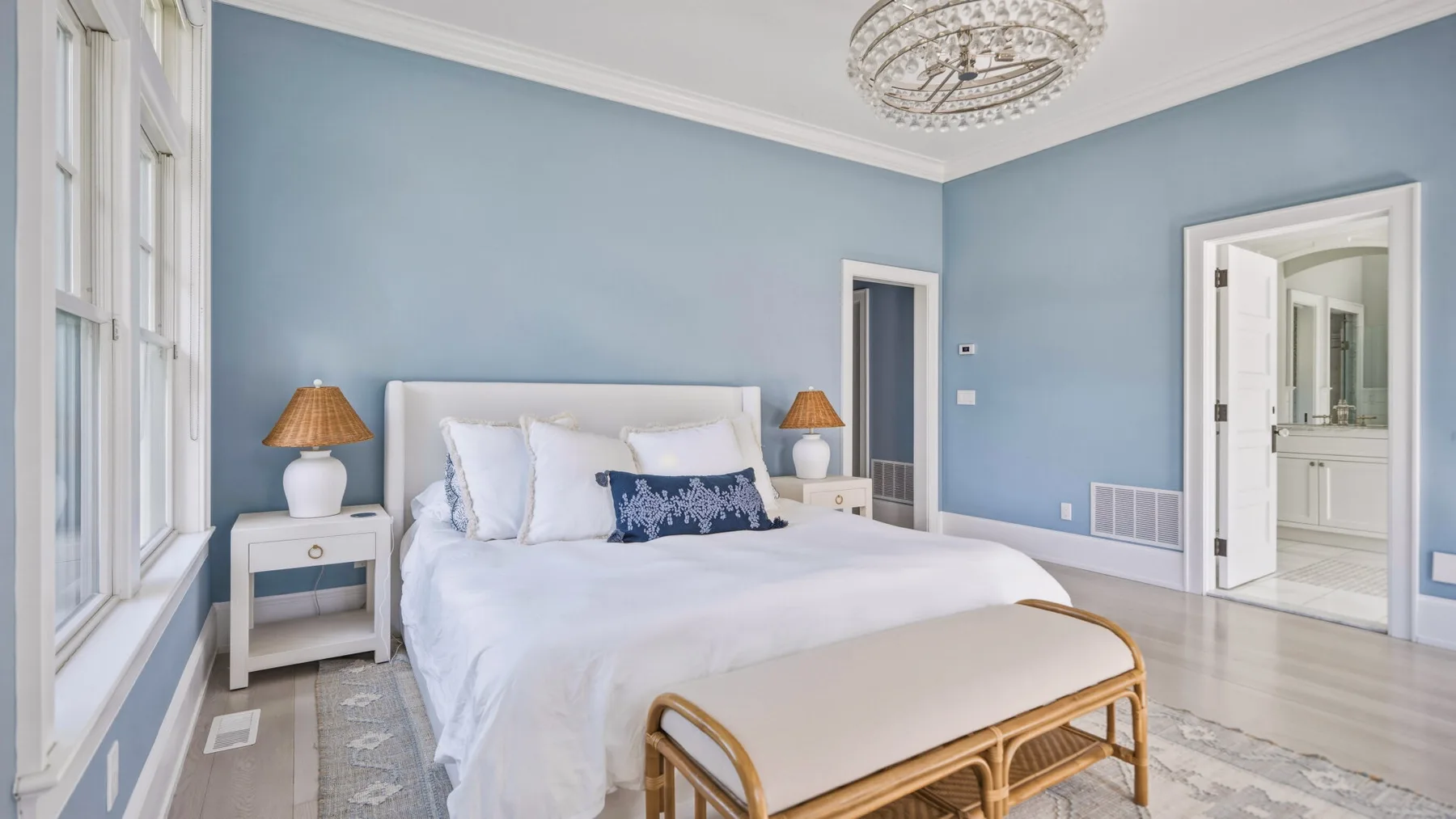 A bright bedroom with a large bed, bedside tables, and pale blue walls.