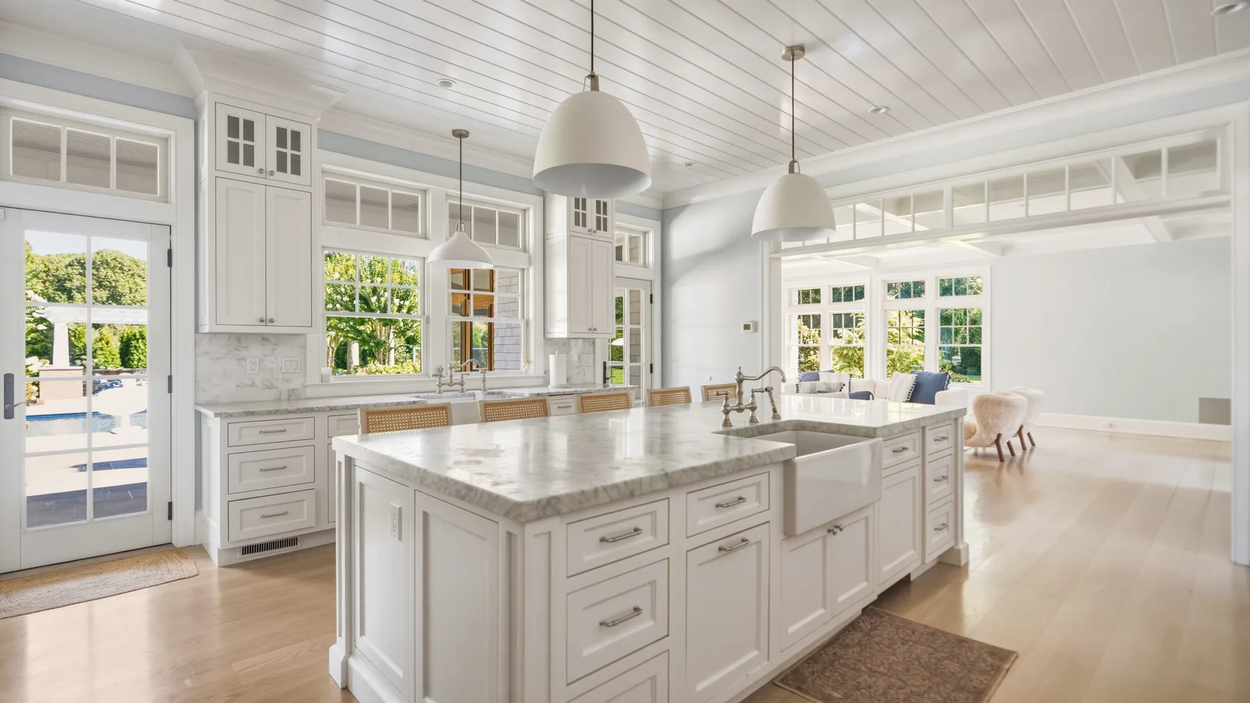 A bright kitchen with a large central island, white cabinetry, and windows.