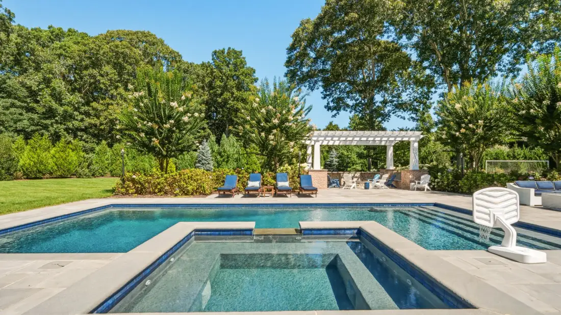 An outdoor swimming pool and spa sit beside a landscaped garden.