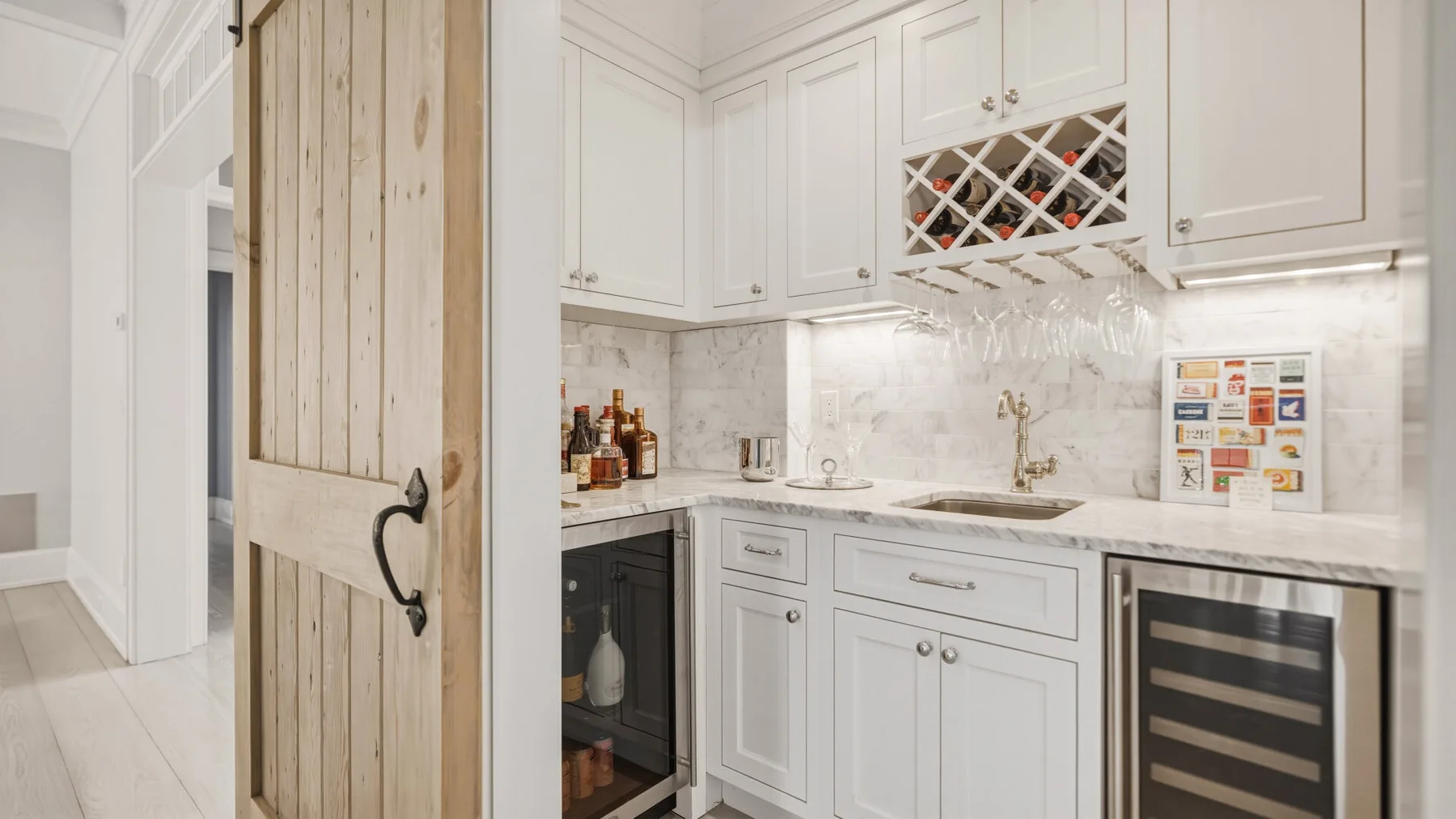 A bright kitchen with white cabinetry, a countertop, and a wooden sliding door.