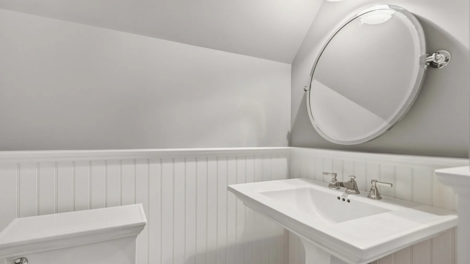 A bathroom vanity with a sink and large round mirror.