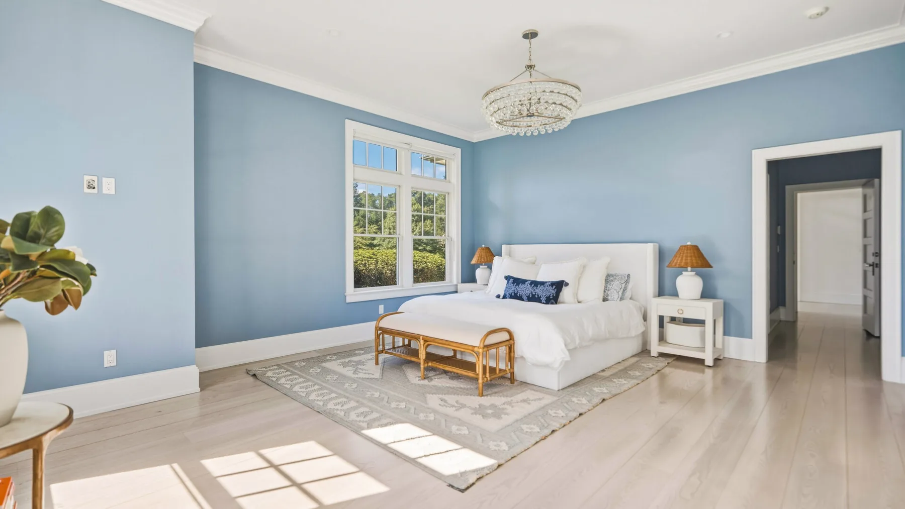 A light blue bedroom with a white bed beside a window.