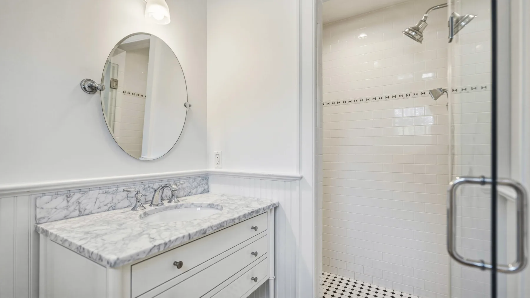 A bright bathroom with a marble-pattern vanity and a tiled shower.