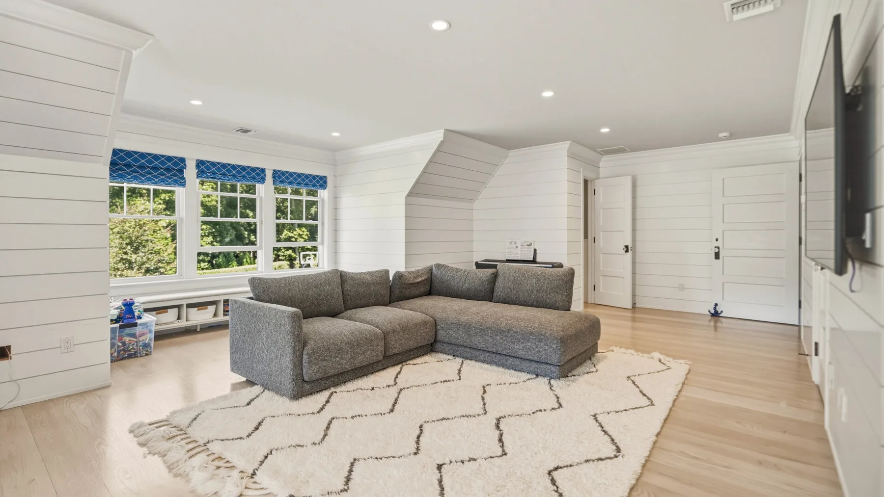 A bright living room features a sectional seating area and a patterned rug.
