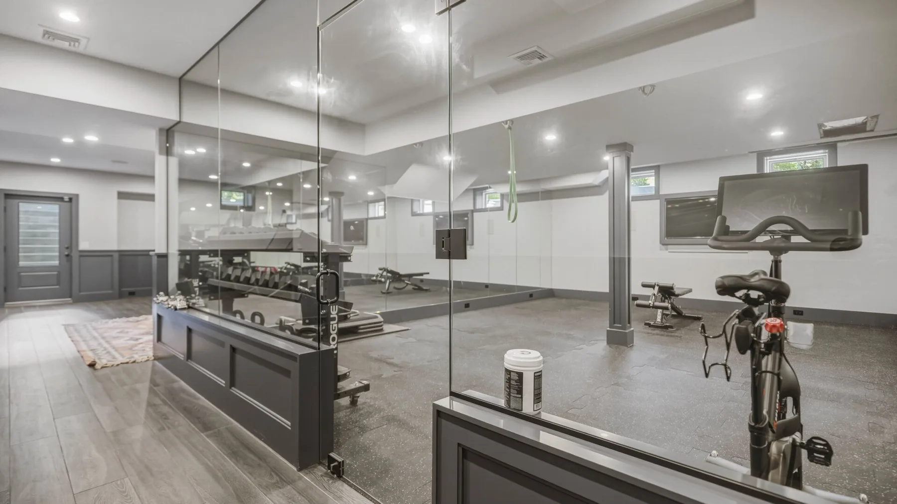 A gym with exercise equipment and a glass-walled workout area.