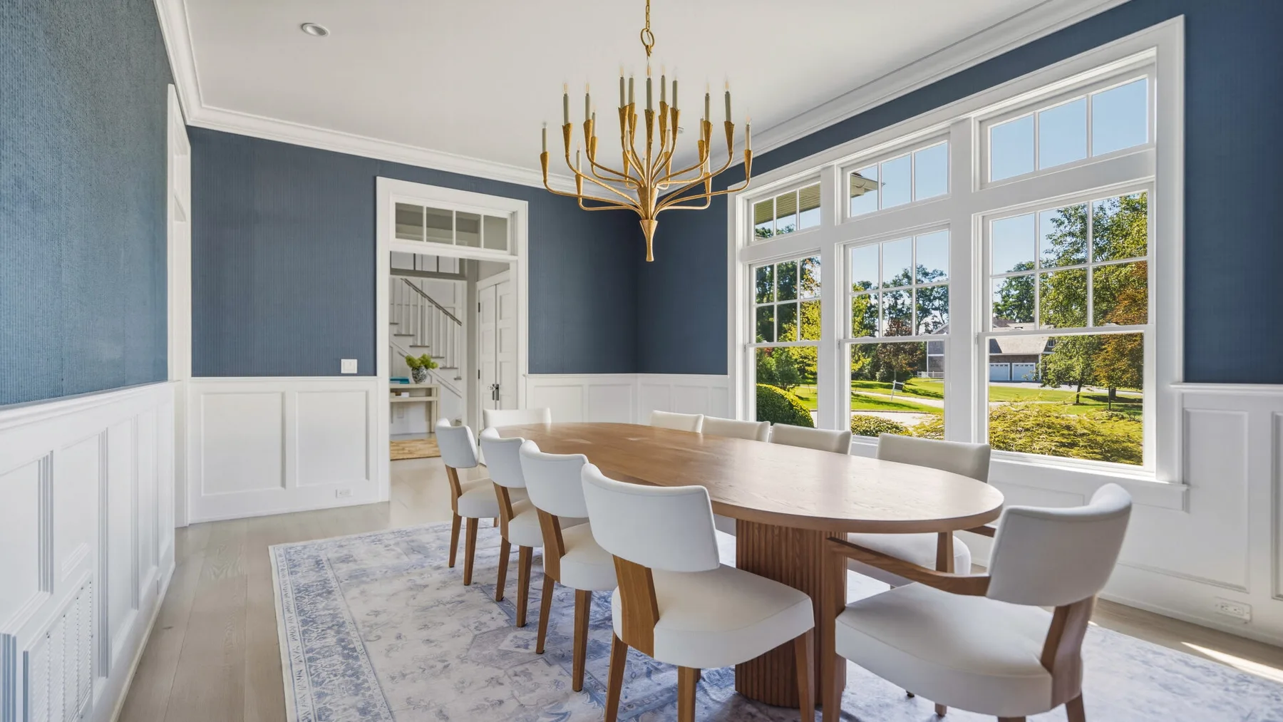 A bright dining room with a long table beside large windows.