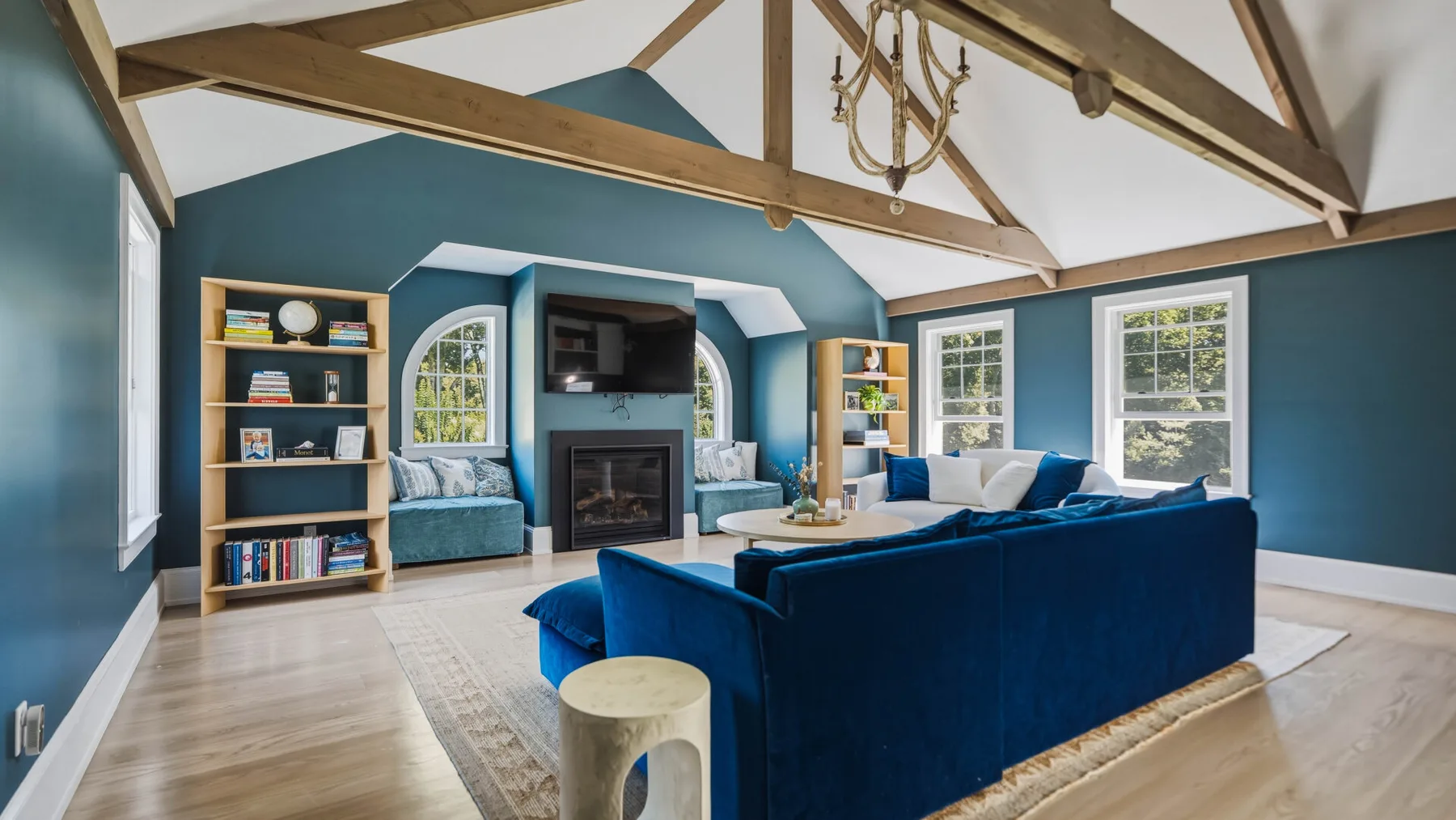 A vaulted living room with blue seating arranged around a fireplace.