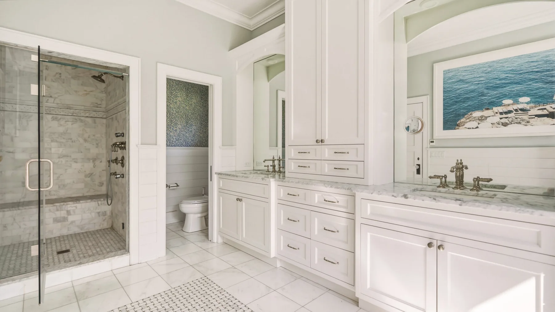 A bright bathroom with a glass shower and a long white vanity.