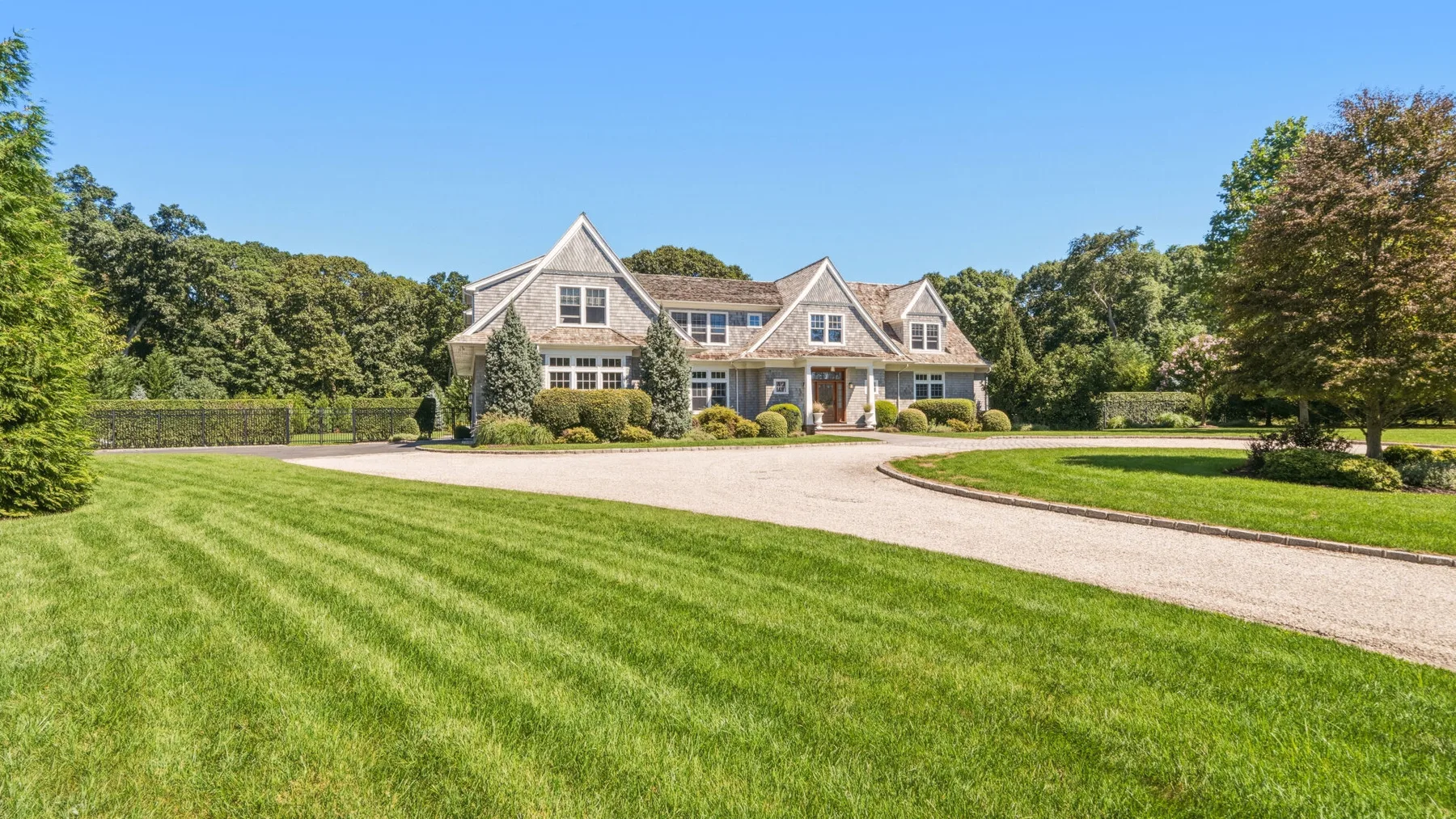 A large house stands behind a curved driveway and broad green lawn.