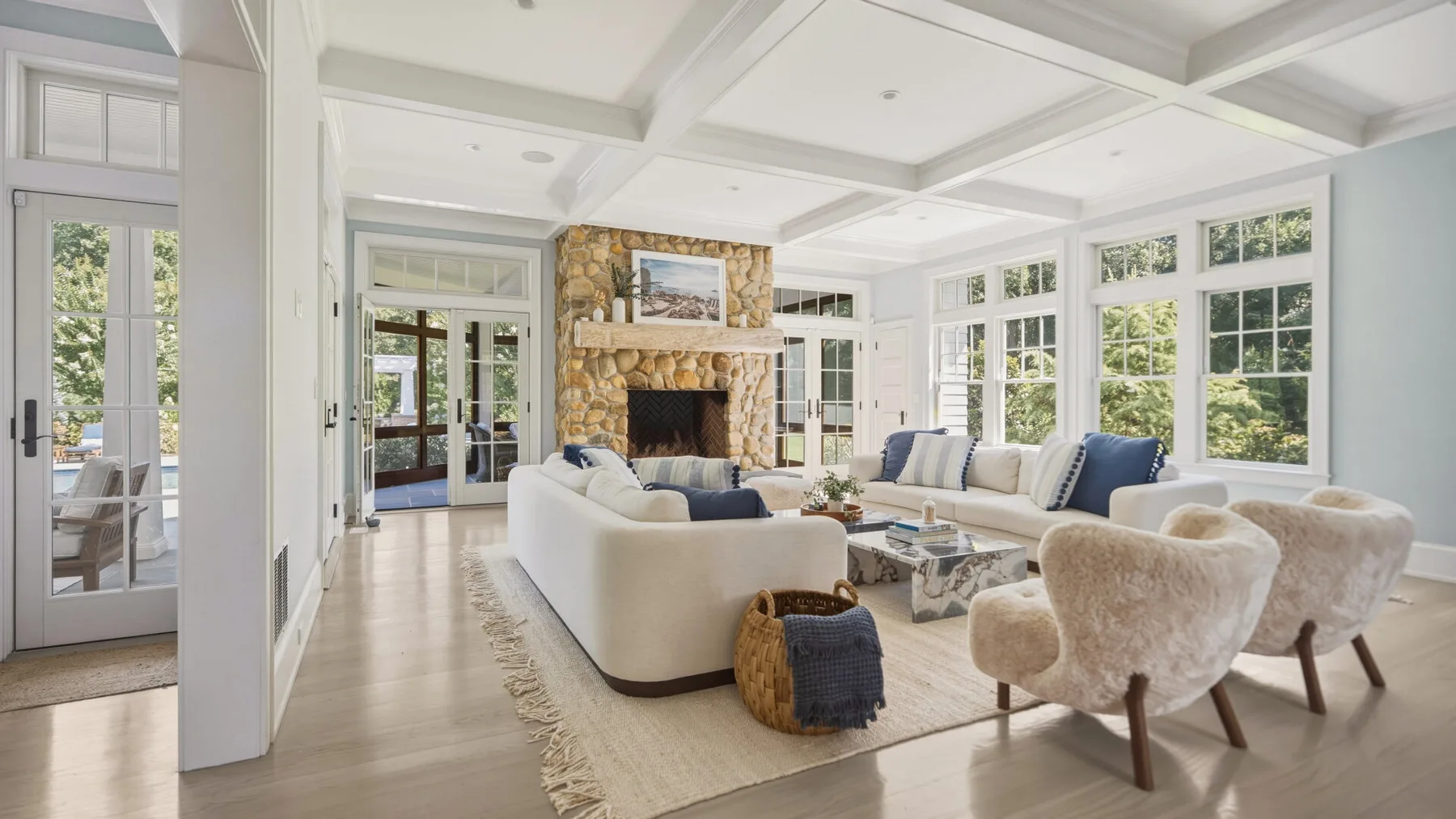 A bright living room with a stone fireplace and seating arranged around a coffee table.