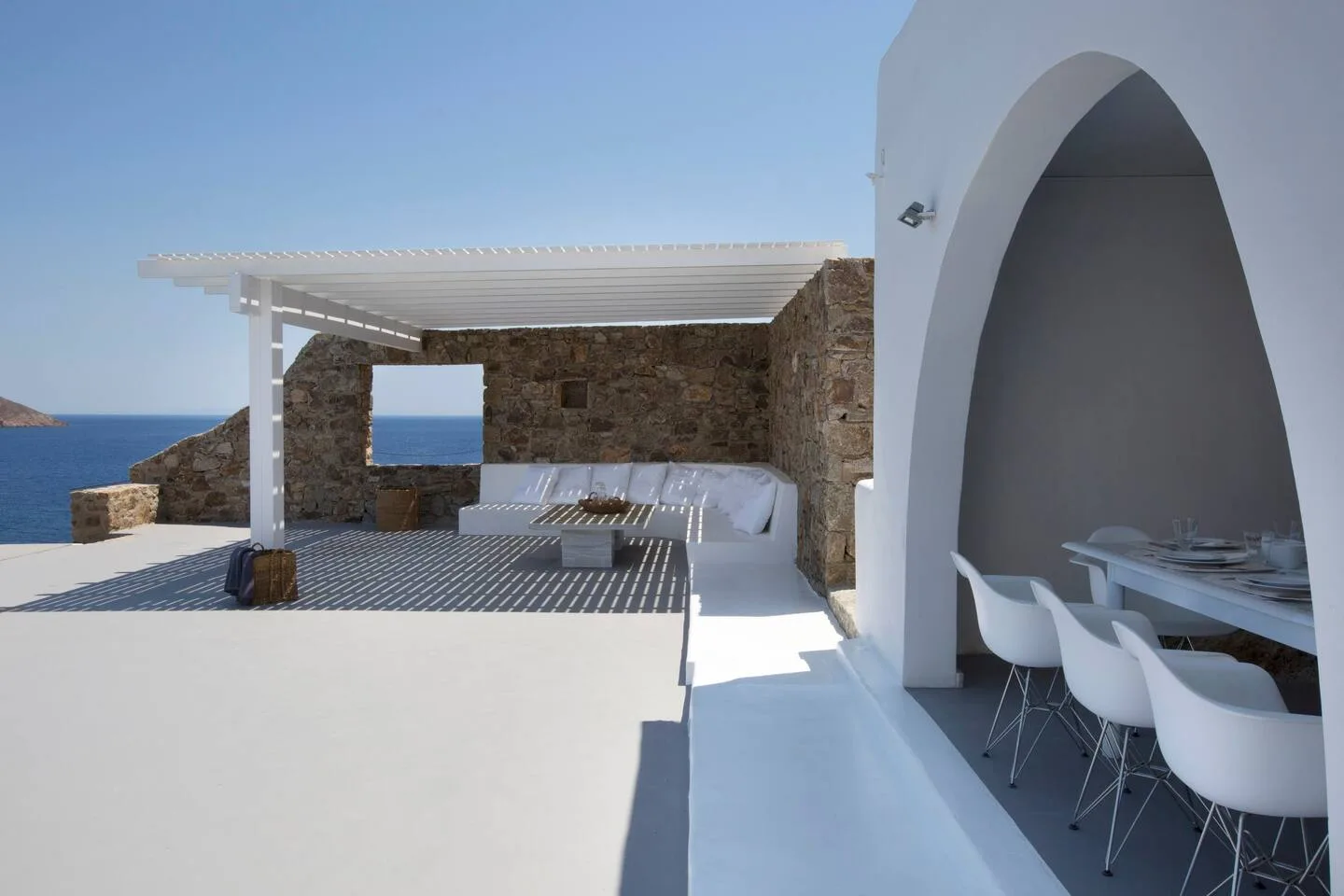 A seaside terrace with a shaded seating area and outdoor dining table.