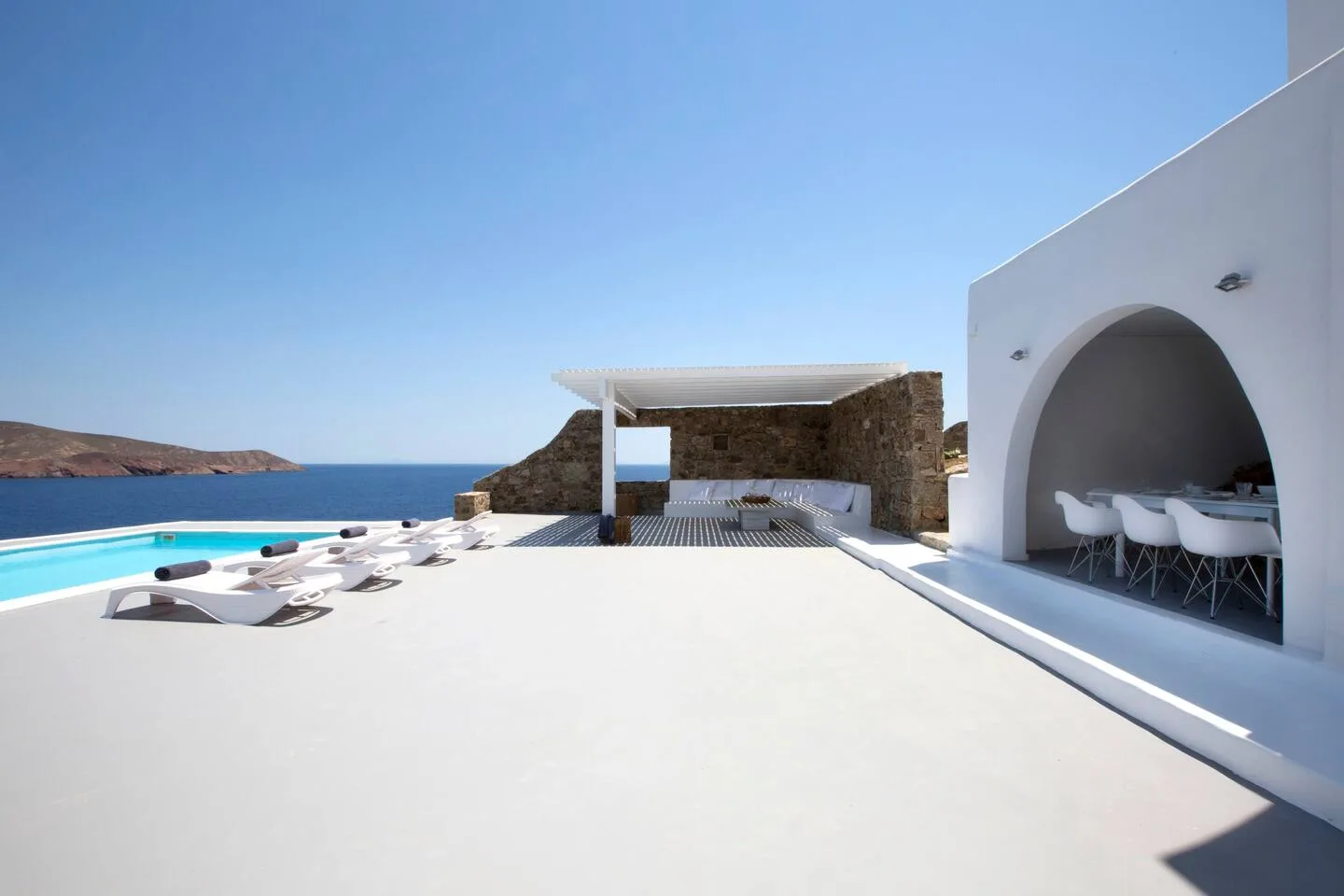 A seaside terrace with a swimming pool and lounge seating.