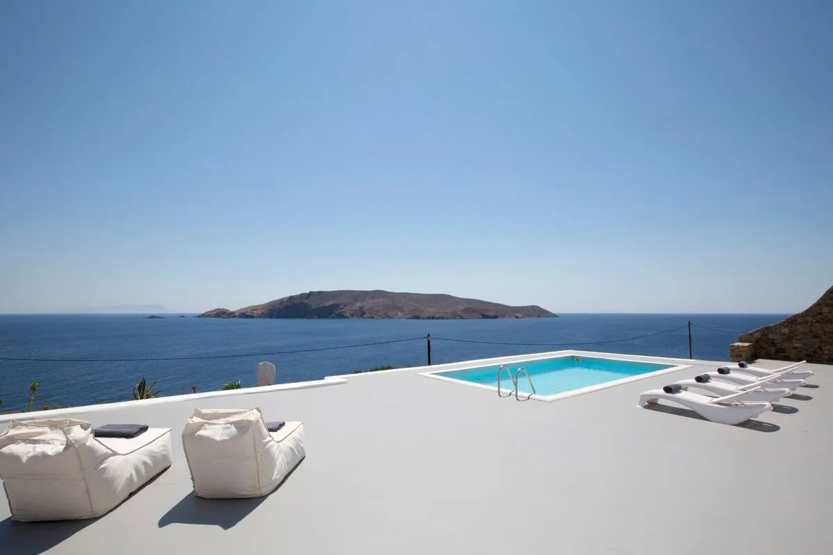 A seaside pool terrace with lounge seating and views of the island.