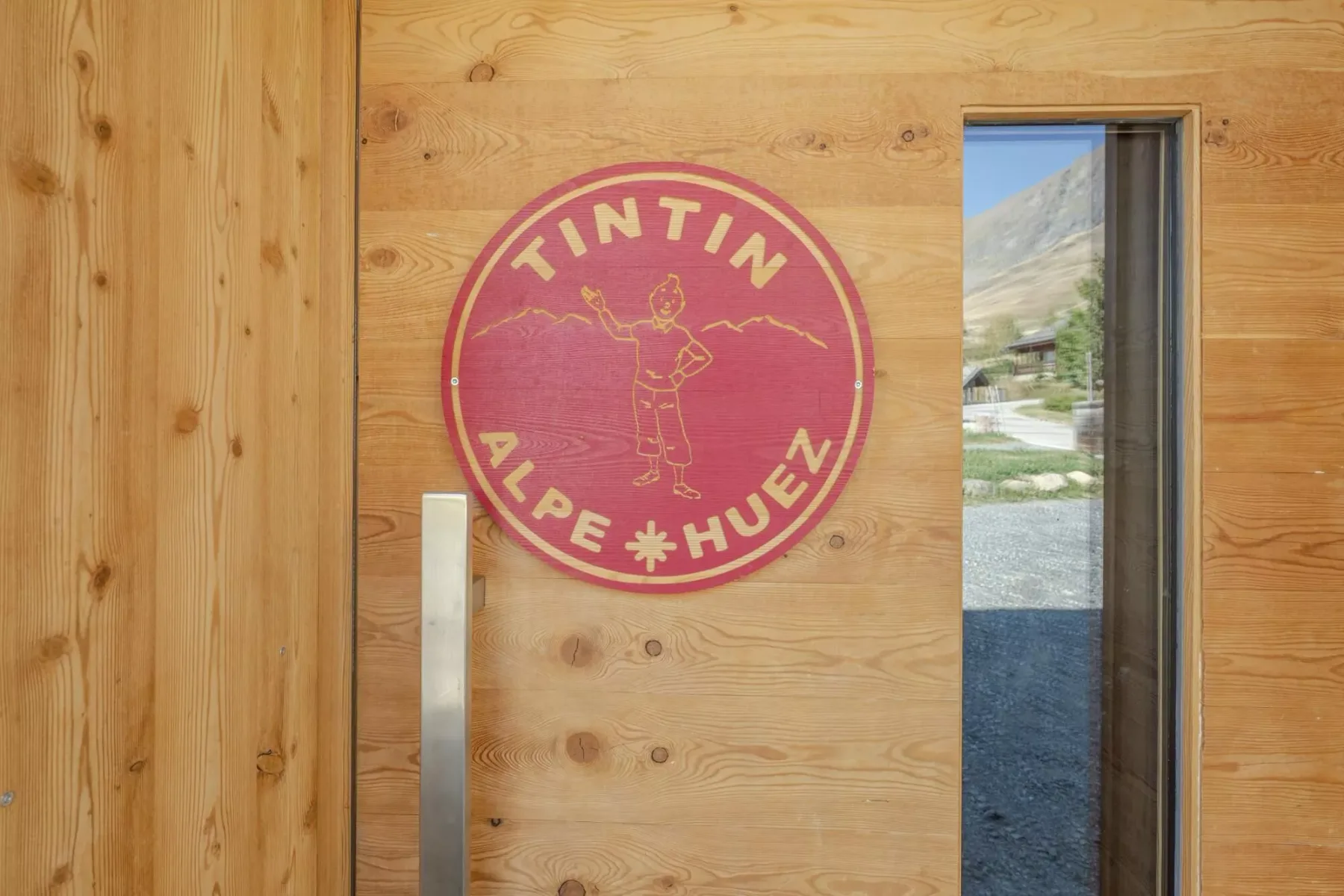 A wooden door with a round red emblem beside a narrow window.