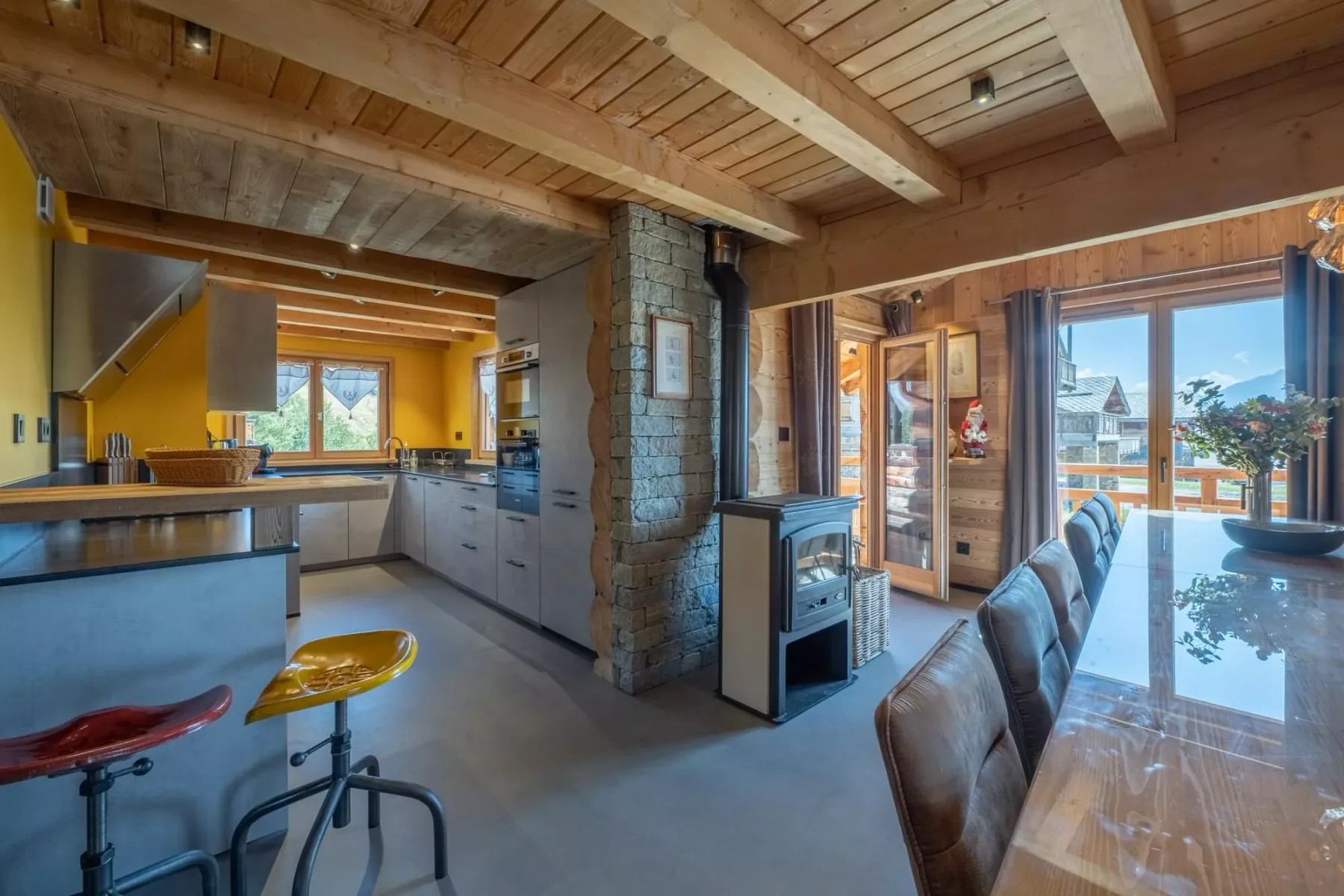 An open-plan kitchen and dining area with wood-paneled ceilings and large windows.