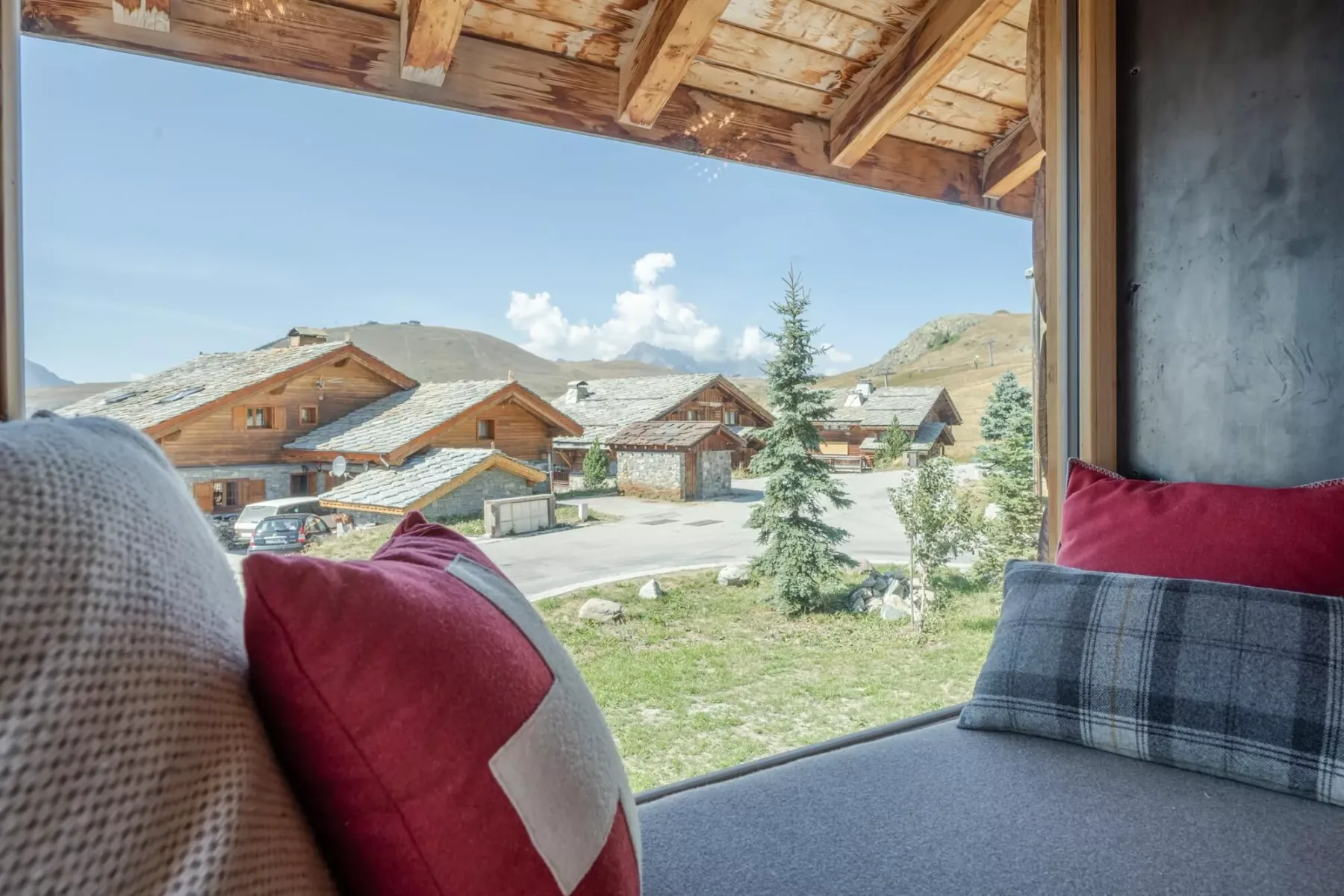 A seating area overlooks wooden buildings and a mountain landscape.