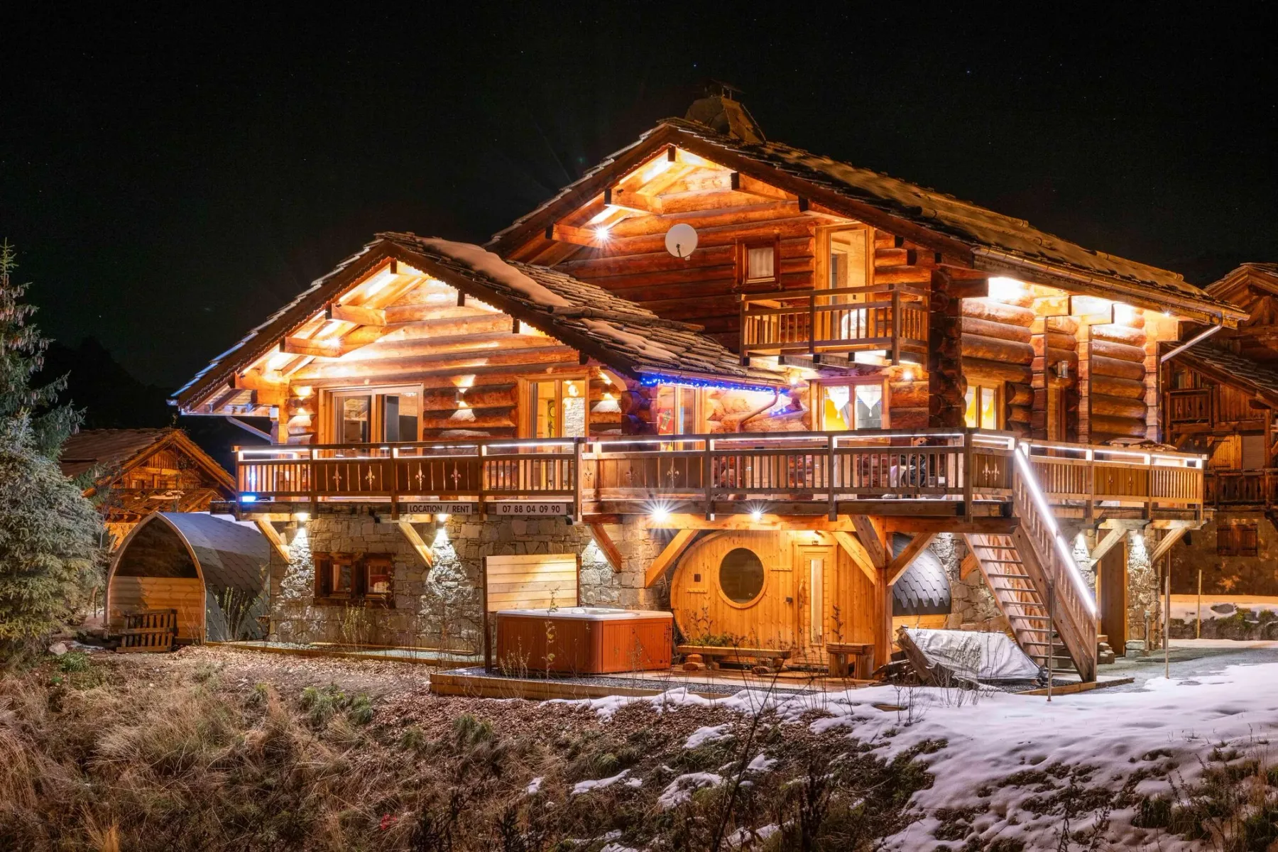A large wooden chalet glows with warm lights against the night sky.