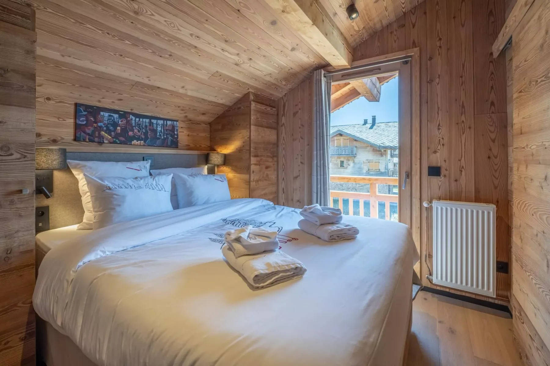 A wood-paneled bedroom with a neatly made bed and an open balcony door.