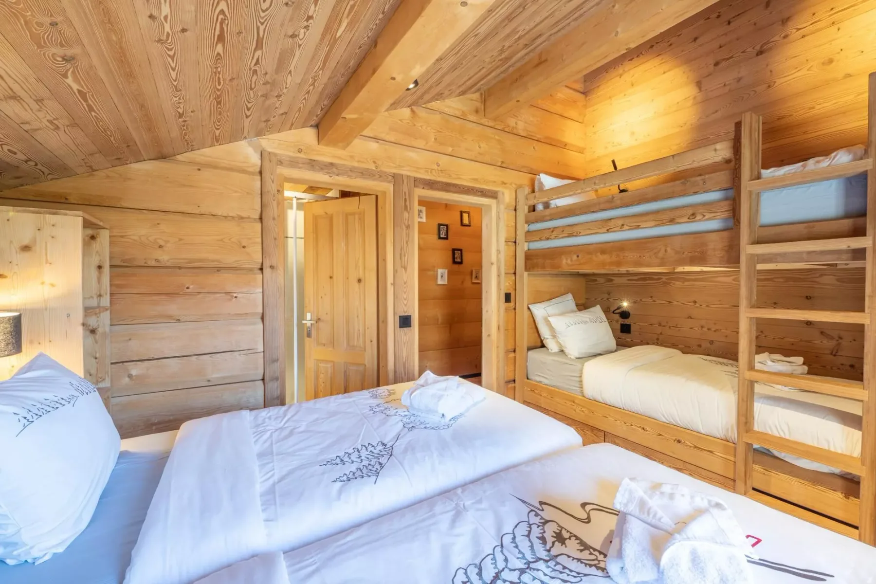 A wood-paneled bedroom with bunk beds and bedding.