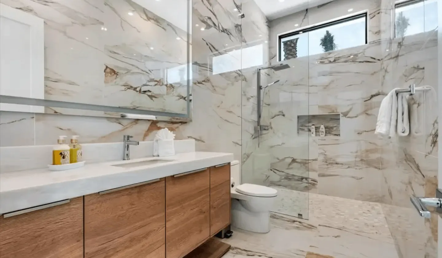A bright bathroom with a long vanity, toilet, and glass shower.