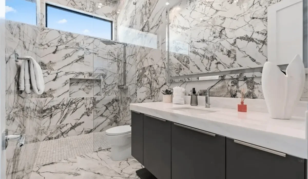 A marble bathroom with a long vanity and a toilet.