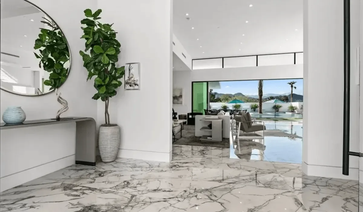 A bright modern interior opens onto a living area and a poolside view.