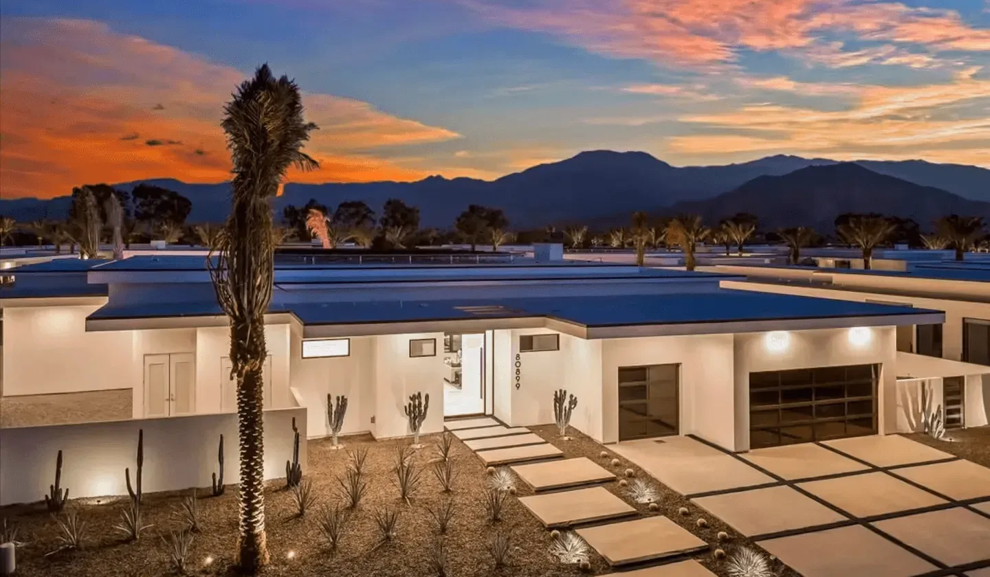 A modern single-story building sits beneath a colorful sunset sky.
