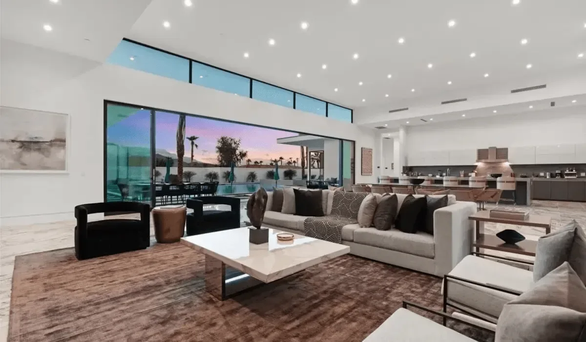 A bright open-plan living room with a seating area and kitchen.