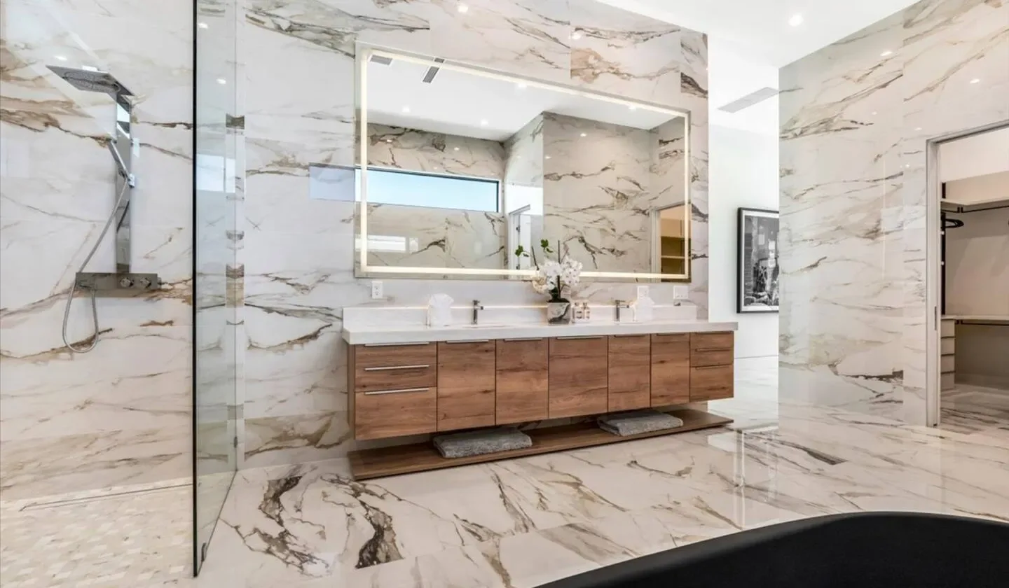 A marble-clad bathroom with a floating vanity and large mirror.