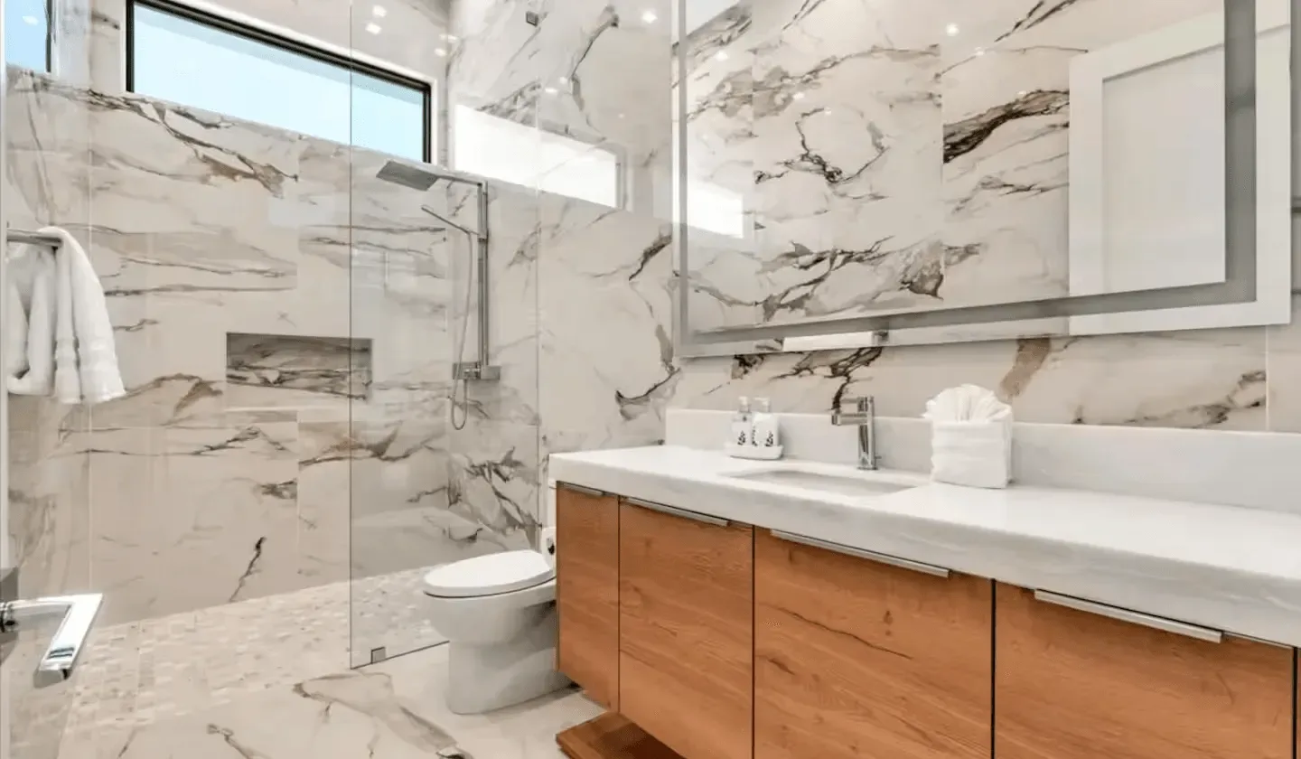 A bright bathroom with a glass shower and a wood vanity.
