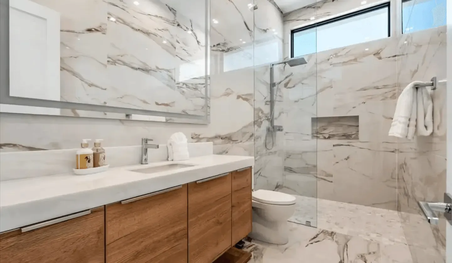 A bright bathroom with a long vanity and glass shower.