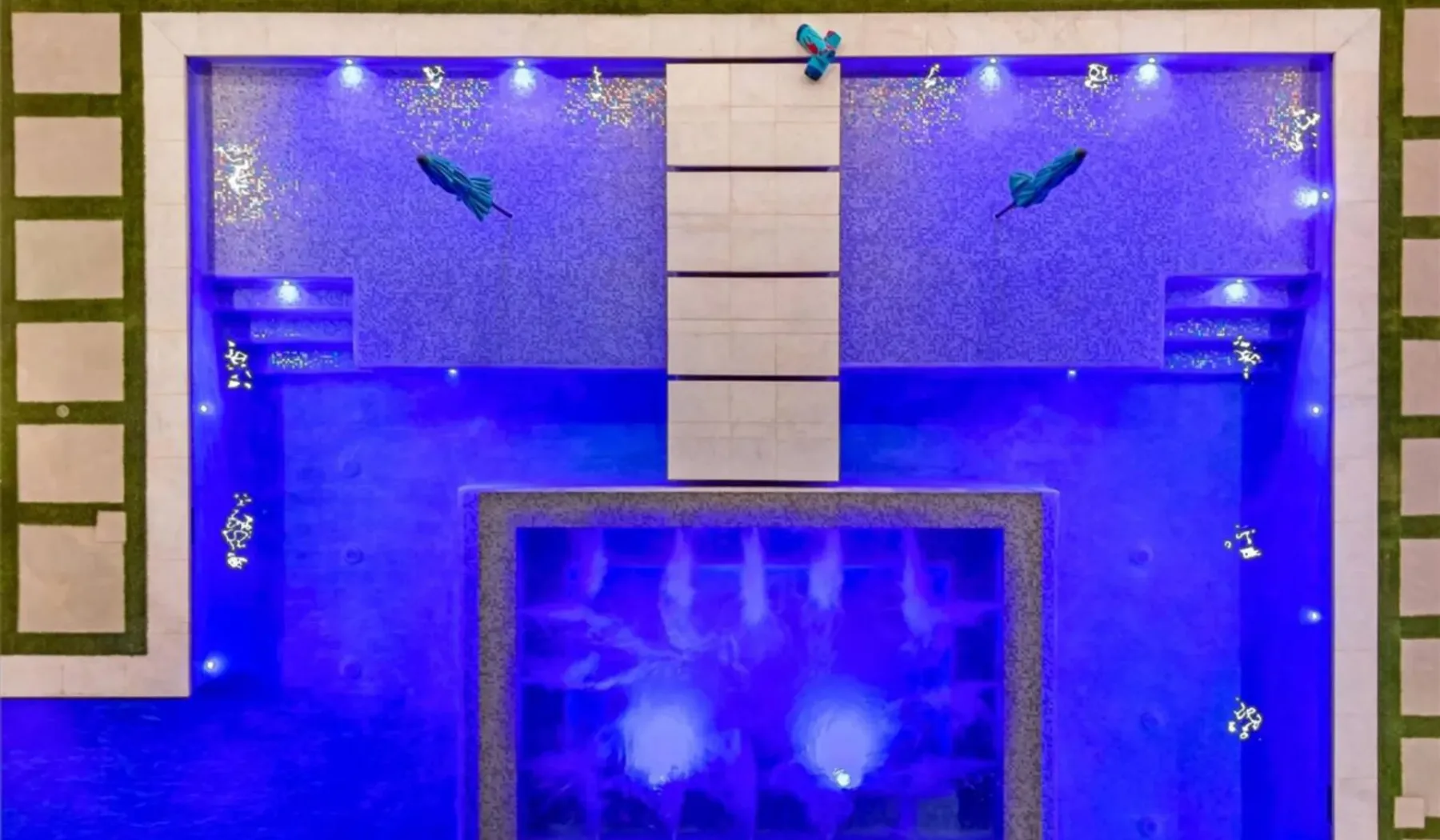 A blue-lit indoor water feature with bright lights and a tiled border.