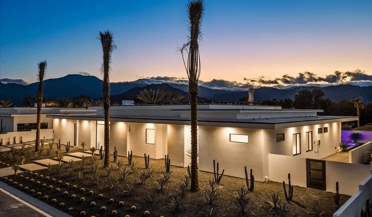 A modern single-story building stands in a desert landscape at dusk.