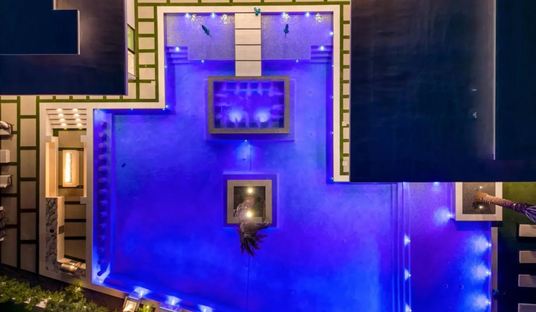 A blue-lit indoor pool sits beneath dark ceiling panels.