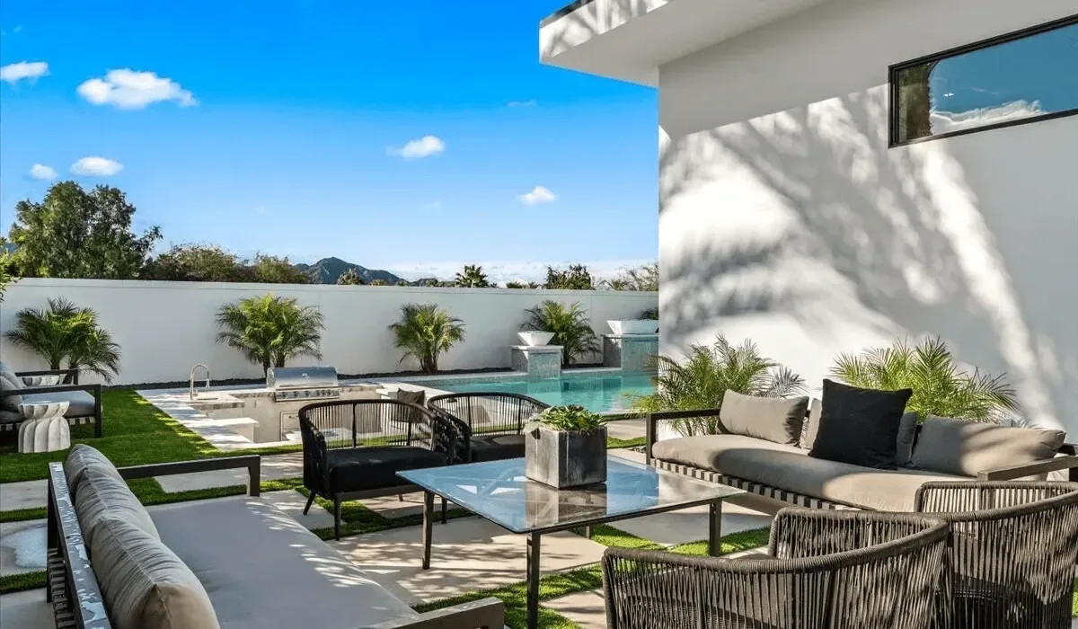 An outdoor lounge and dining area beside a swimming pool.