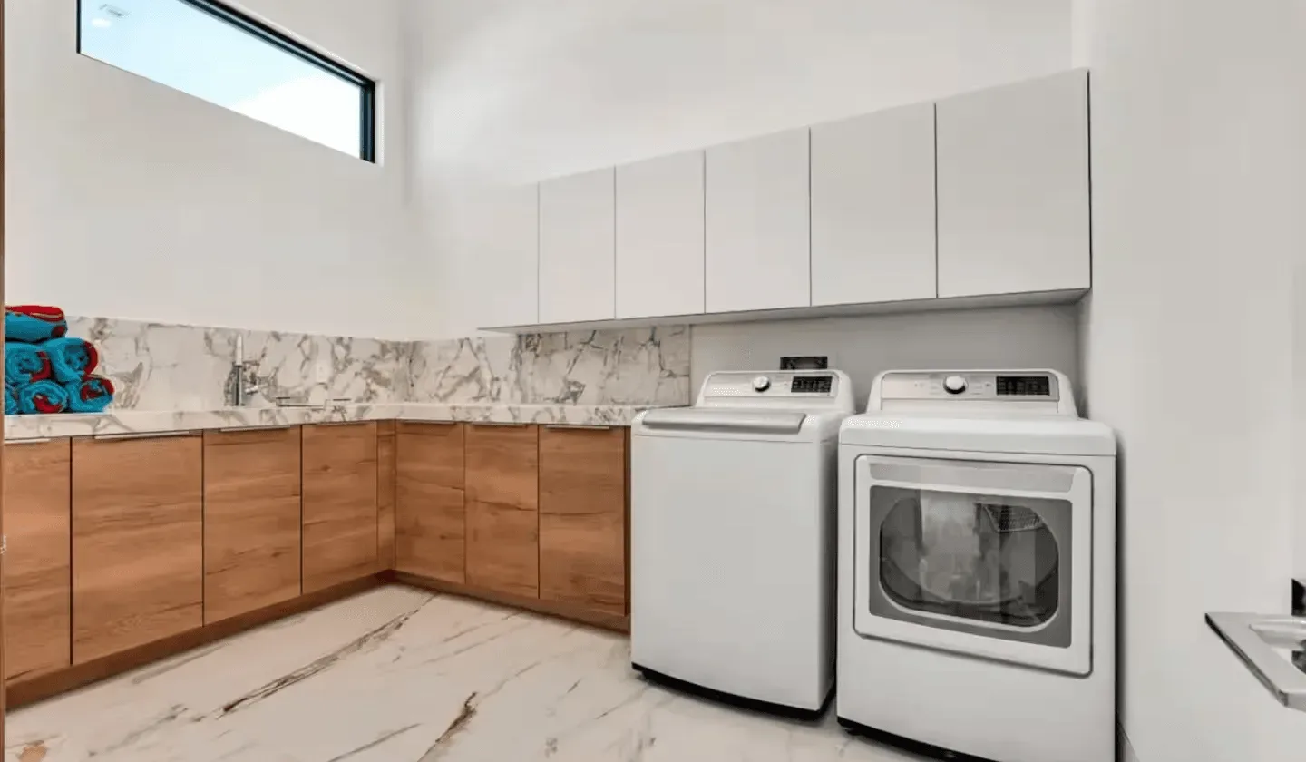 A laundry room with a washer and dryer beneath white cabinets.