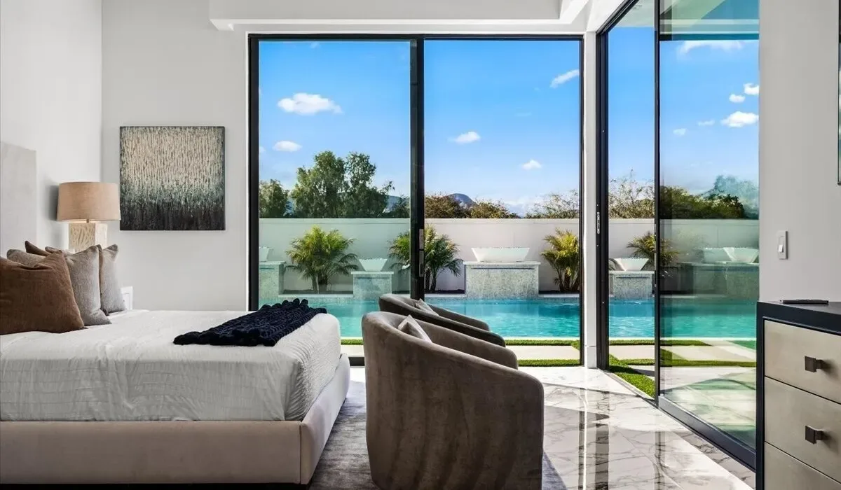 A bright bedroom opens onto a terrace with a swimming pool.