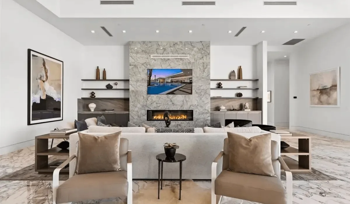 A bright living room with seating arranged around a fireplace and television.
