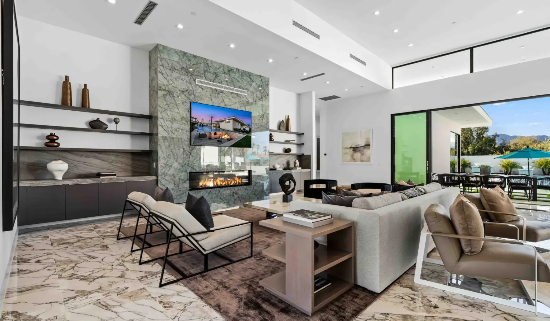 A modern living room with a seating area and wide glass doors opening to a patio.