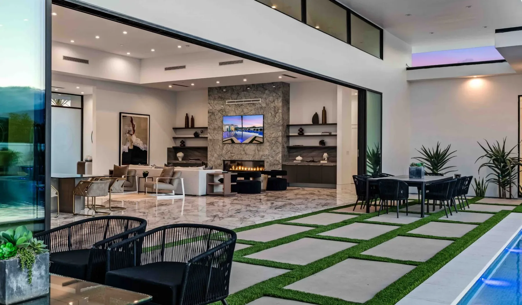 Modern open-plan living and dining area with seating beside a pool.