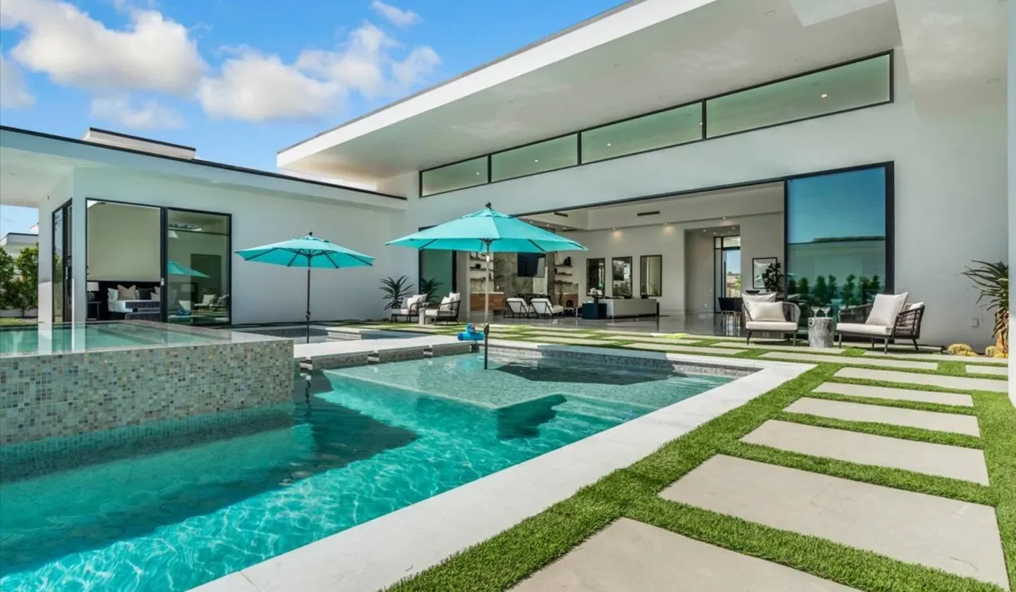 A modern house opens onto a swimming pool and a grass-lined patio.