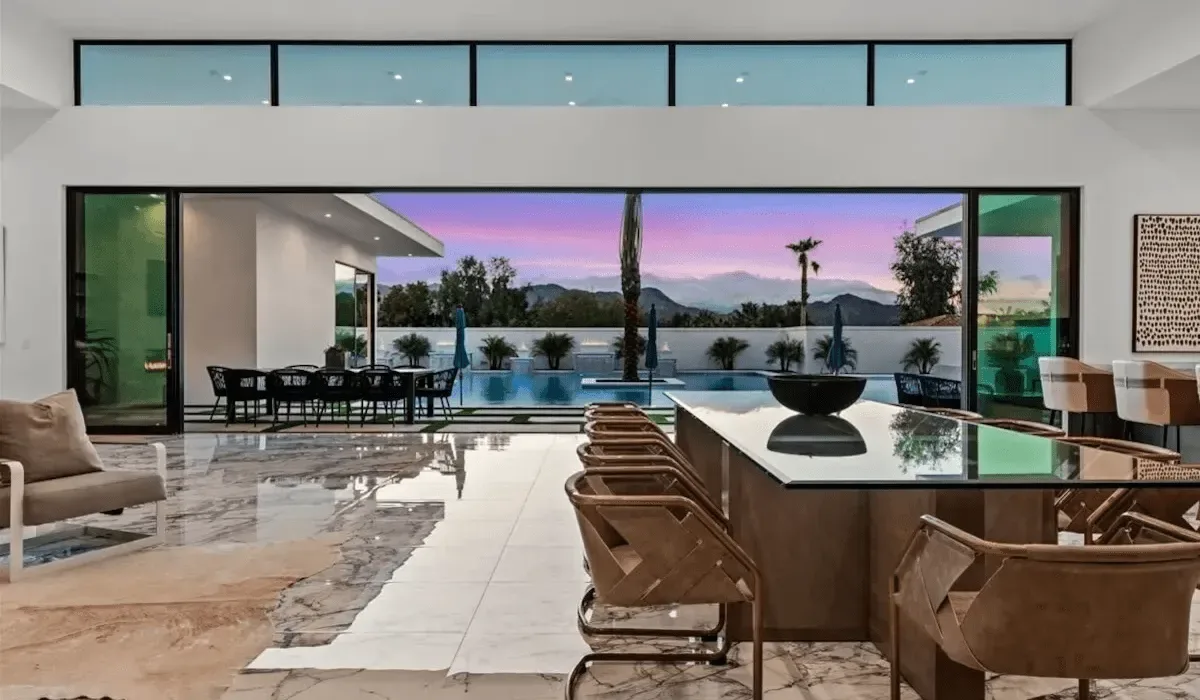 An open-plan dining and kitchen area faces a pool and mountain view.